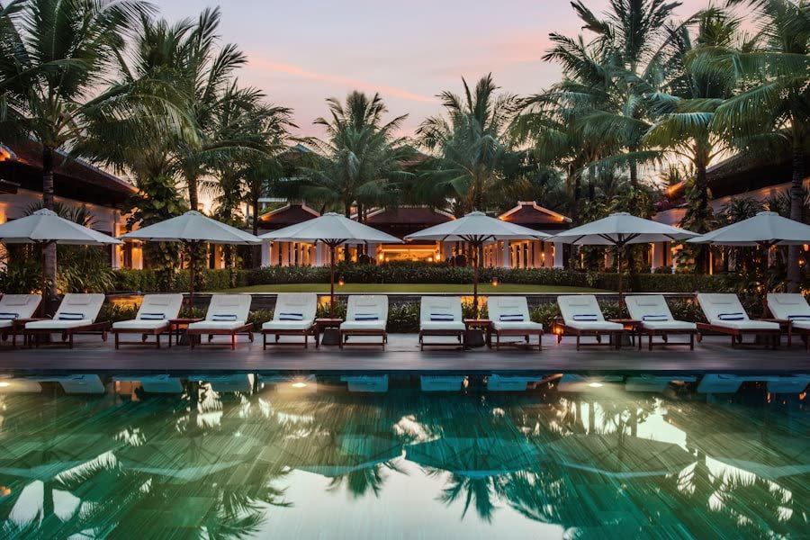 Resort pool lined with loungers at dusk